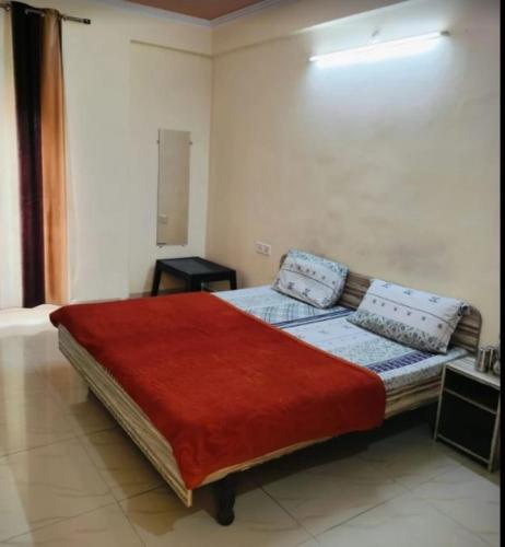a bedroom with a large bed with a red blanket at The Gopi Dham Hotel in Haridwār