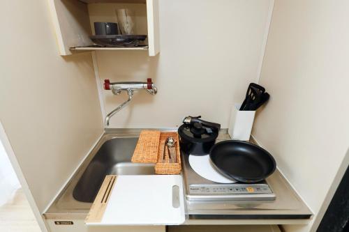 a kitchen with a sink and a frying pan at Piazza-U Yutenji by Tranova in Tokyo