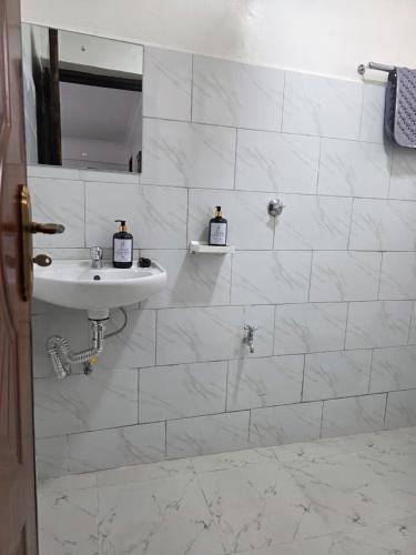 a white bathroom with a sink and a mirror at Jay Homes -Ultra Modern Naivegas Apartments in Naivasha