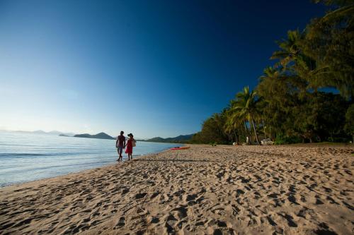 a man and woman walking on the beach at The Reef Retreat Palm Cove in Palm Cove