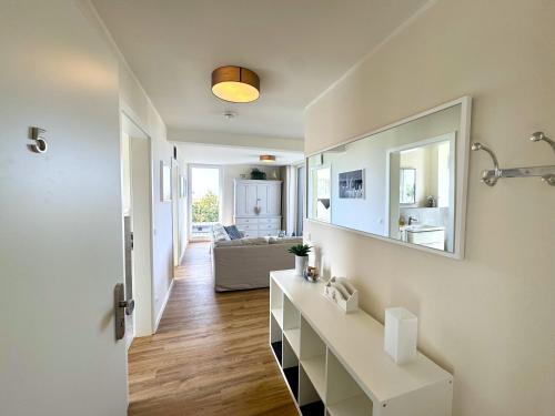 a living room with a white table and a mirror at Penthouse Seeblick am Leuchtturm in Fehmarn