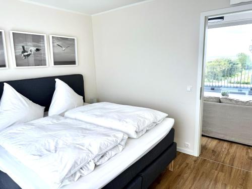 a bed with white sheets in a room with a window at Penthouse Seeblick am Leuchtturm in Fehmarn