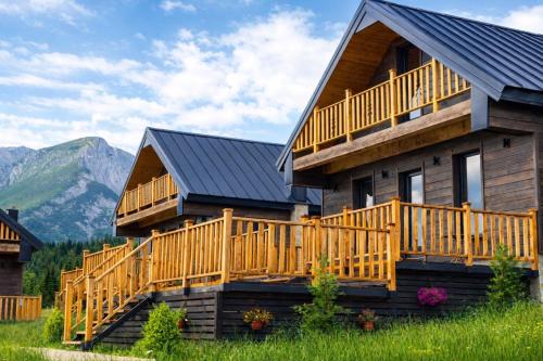 a log cabin with a deck and mountains in the background at Adria Nord Chalets in Žabljak