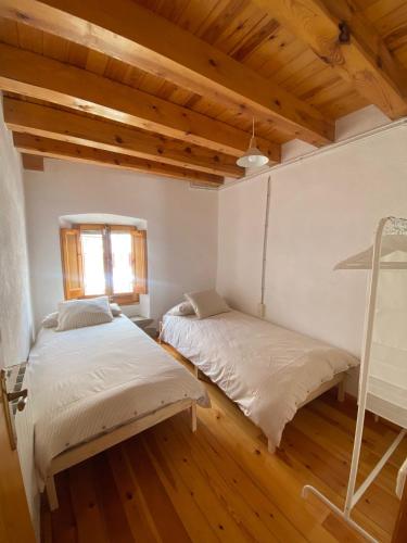 two beds in a room with wooden floors and a window at Ca La Pausa in Alpens