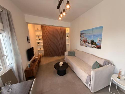 a living room with a couch and a tv at White Swallow Suite Santorini in Vourvoúlos