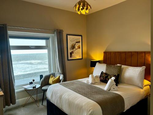 a bedroom with a bed and a window with the ocean at Hotel No5, Beachfront with Free Private Car Park in Llandudno