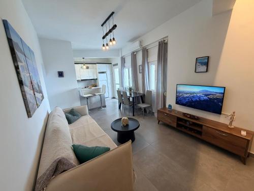 a living room with a couch and a flat screen tv at White Swallow Suite Santorini in Vourvoúlos