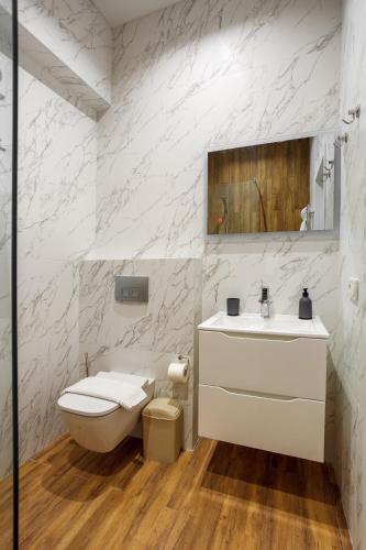 a white bathroom with a toilet and a sink at Five seasons Family in Odesa