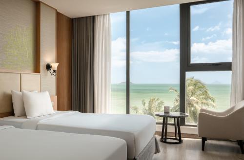 a hotel room with two beds and a large window at Navada Beach Hotel in Nha Trang