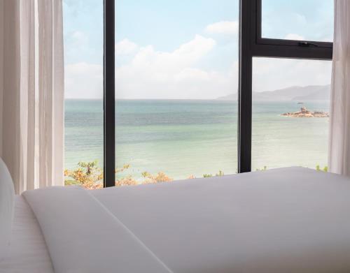 a bedroom with a large window overlooking the ocean at Navada Beach Hotel in Nha Trang