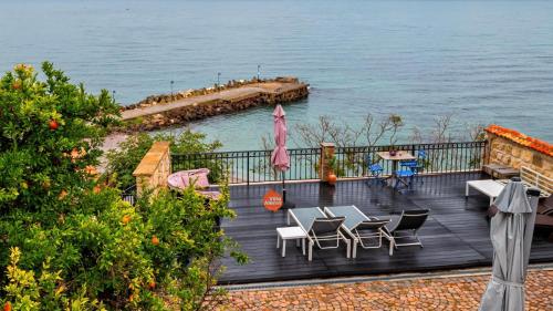 a wooden deck with tables and chairs next to the water at Villa Alenor – Sea View & Beach Access in Nesebar