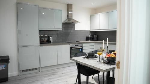 a kitchen with white cabinets and a table with glasses of wine at The Emerald Residence - Leicester - City Centre, Sofa Bed, Parking, Free WiFi, Netflix in Leicester