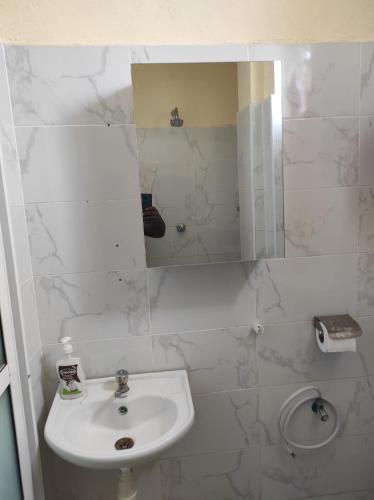a white bathroom with a sink and a mirror at GCG STAYS ltd in Mtwapa