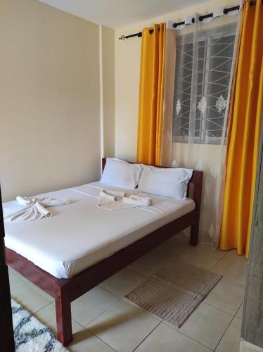 a bed in a room with an orange curtain at GCG STAYS ltd in Mtwapa