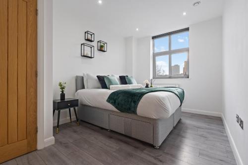 a white bedroom with a large bed with a window at The Emerald Residence - Leicester - City Centre, Sofa Bed, Parking, Free WiFi, Netflix in Leicester