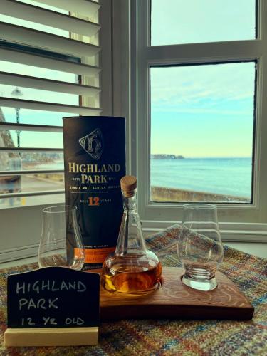 a bottle of highland parkark and a book and glasses at Sea Crest - Beachfront Escape with Whisky Snug in Cullen