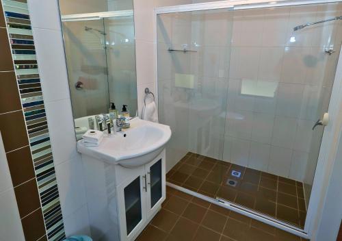 a white bathroom with a sink and a shower at Beltana Villas in Pokolbin