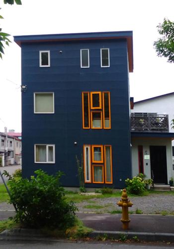 a blue house with orange doors and a yellow fire hydrant at Guest House Annabel in Hakodate