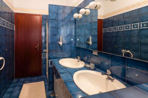 a blue tiled bathroom with two sinks and a mirror at Viewpoint House in Alzano Lombardo
