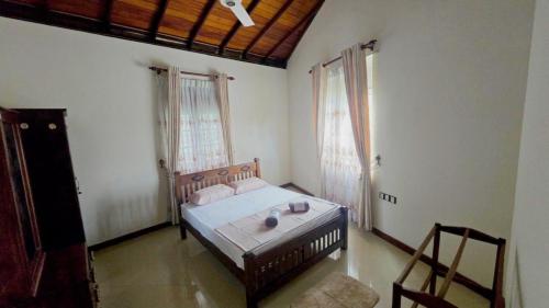 a bedroom with a bed and two windows and a chair at The Kandy City Townhouse in Kandy