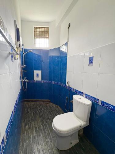 a bathroom with a toilet and blue and white tiles at The Kandy City Townhouse in Kandy