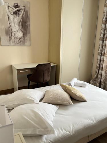 a bed with white sheets and a chair in a room at Hôtel Le Square in Capvern