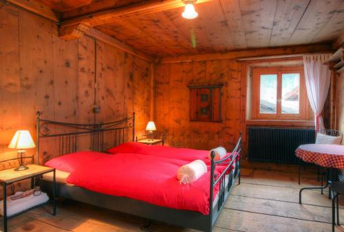 a bedroom with a red bed in a room with wooden walls at Chasa Jaro in Santa Maria Val Müstair