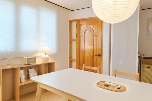 a dining room with a white table and a lamp at Sai-gil stay in Busan