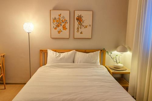 a bedroom with a white bed with two pictures on the wall at Sai-gil stay in Busan
