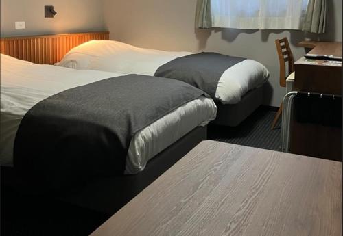 a hotel room with two beds and a desk at Atto Business Hotel Ichinoseki in Ichinoseki