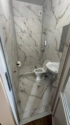 a white bathroom with a toilet and a sink at Motel Ararat in Rava-Rusʼka