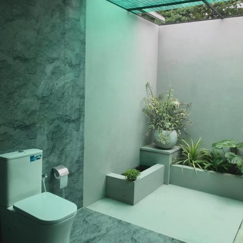 a bathroom with a toilet and some plants at Amelia Villa in Gandara West