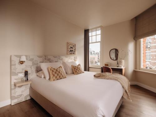 a bedroom with a large white bed and a window at Adam's Museum House in Amsterdam