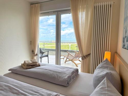 a bedroom with a bed and a view of the ocean at Strandvilla Therese Appartment 5 in Norderney
