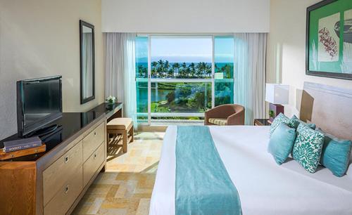 a bedroom with a bed with a television and a window at Mayan Palace at Vidanta Vallarta in Puerto Vallarta
