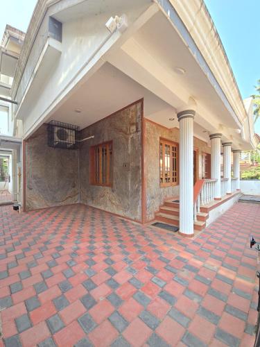 a large building with a brick floor and columns at Spacious 2 Bedroom Private House in Mangalore Fully Air-Conditioned, WiFi & Parking in Mangalore
