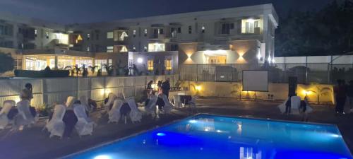a group of people sitting around a swimming pool at night at Golden Alpine Hotel in Yola