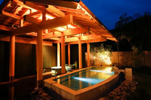 a swimming pool under a wooden pergola at night at Hotel Tokinoza in Kihokucho