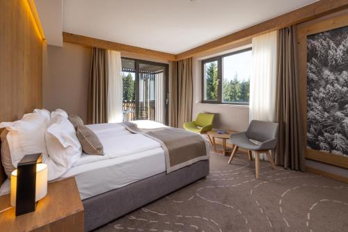 a hotel room with a bed and a desk and chairs at Hotel Monti Spa & Wellness in Igman