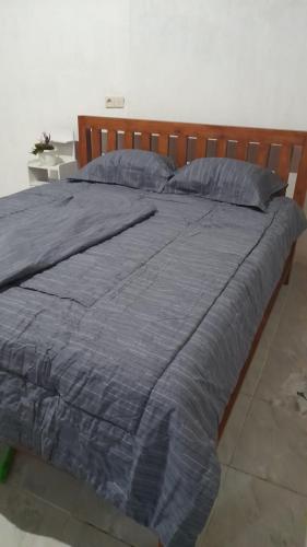 a large bed with a blue comforter and pillows at Bali Home Taksu in Jatiluwih
