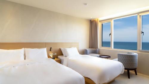 two beds in a hotel room with a view of the ocean at 온더웨이브호텔 in Taesong