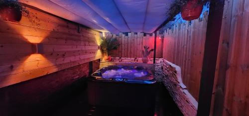 Aphrodite Spa في Balleroy: حمام مزود بحوض استحمام ساخن بإضاءة أرجوانية