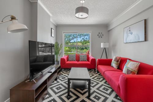 a living room with red couches and a tv at Vibrant Stylish, Cozy Waterfront Downtown in Calgary