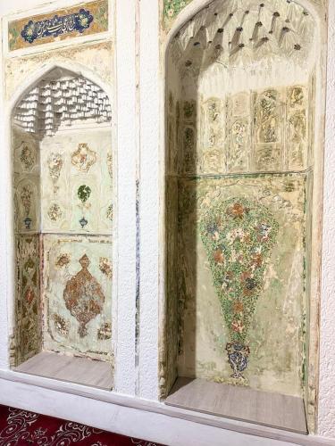 a room with a window with paintings on it at Boutique ALISHER in Bukhara