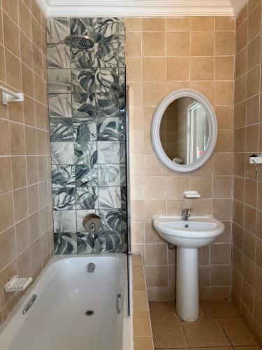 a bathroom with a tub and a sink and a mirror at Nine On Borghorst in Port Elizabeth