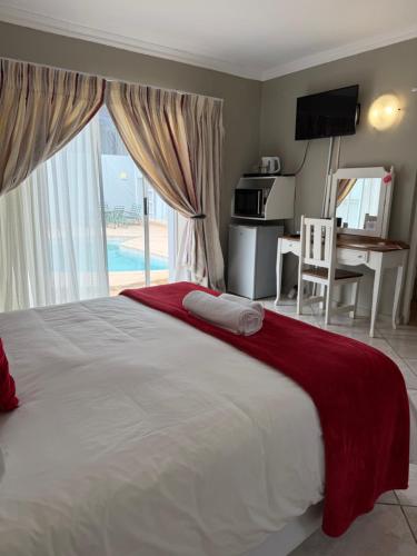 a bedroom with a large bed with a desk and a window at Nine On Borghorst in Port Elizabeth
