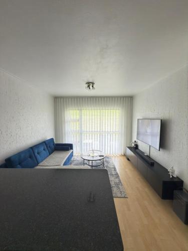 a living room with a blue couch and a tv at The Greenside Getaway in Roodepoort