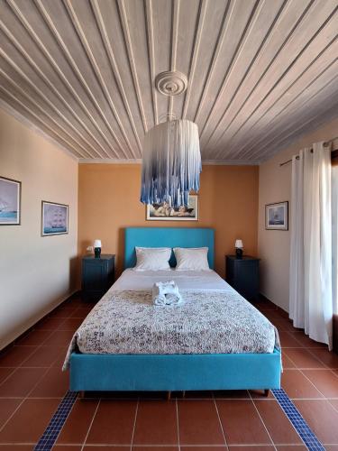 a bedroom with a blue bed and a chandelier at Papa Nero Beach House in Agios Ioannis Pelio