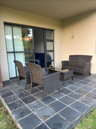 a patio with wicker chairs and a table at The Greenside Getaway in Roodepoort