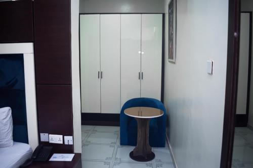 a room with a blue chair and a table and cabinets at Chinbell Luxury Hotel & Suites in Lekki